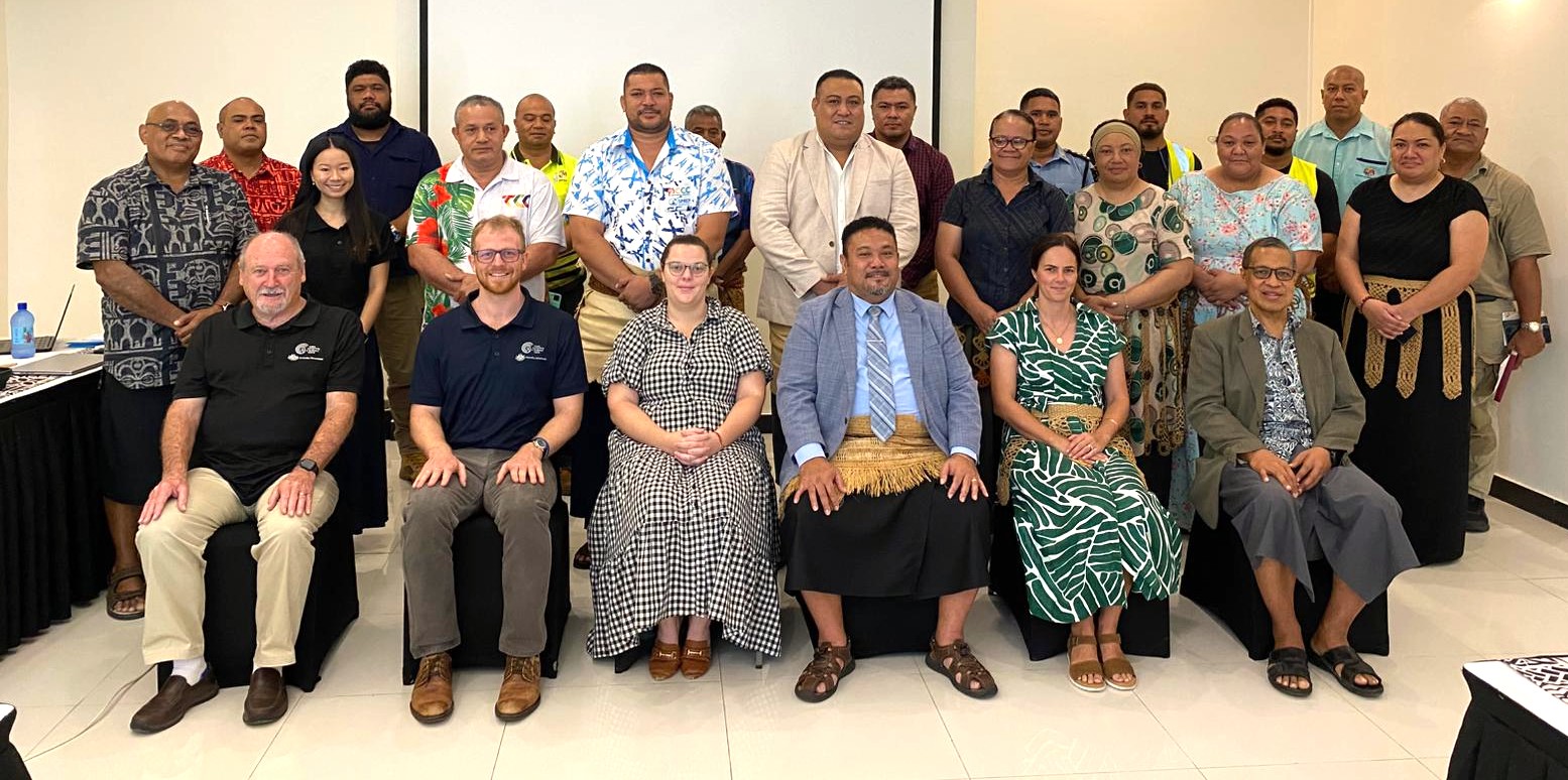 A formal group photo of attendees standing and sitting at meeting in Tonga to discuss  telecommunications. 