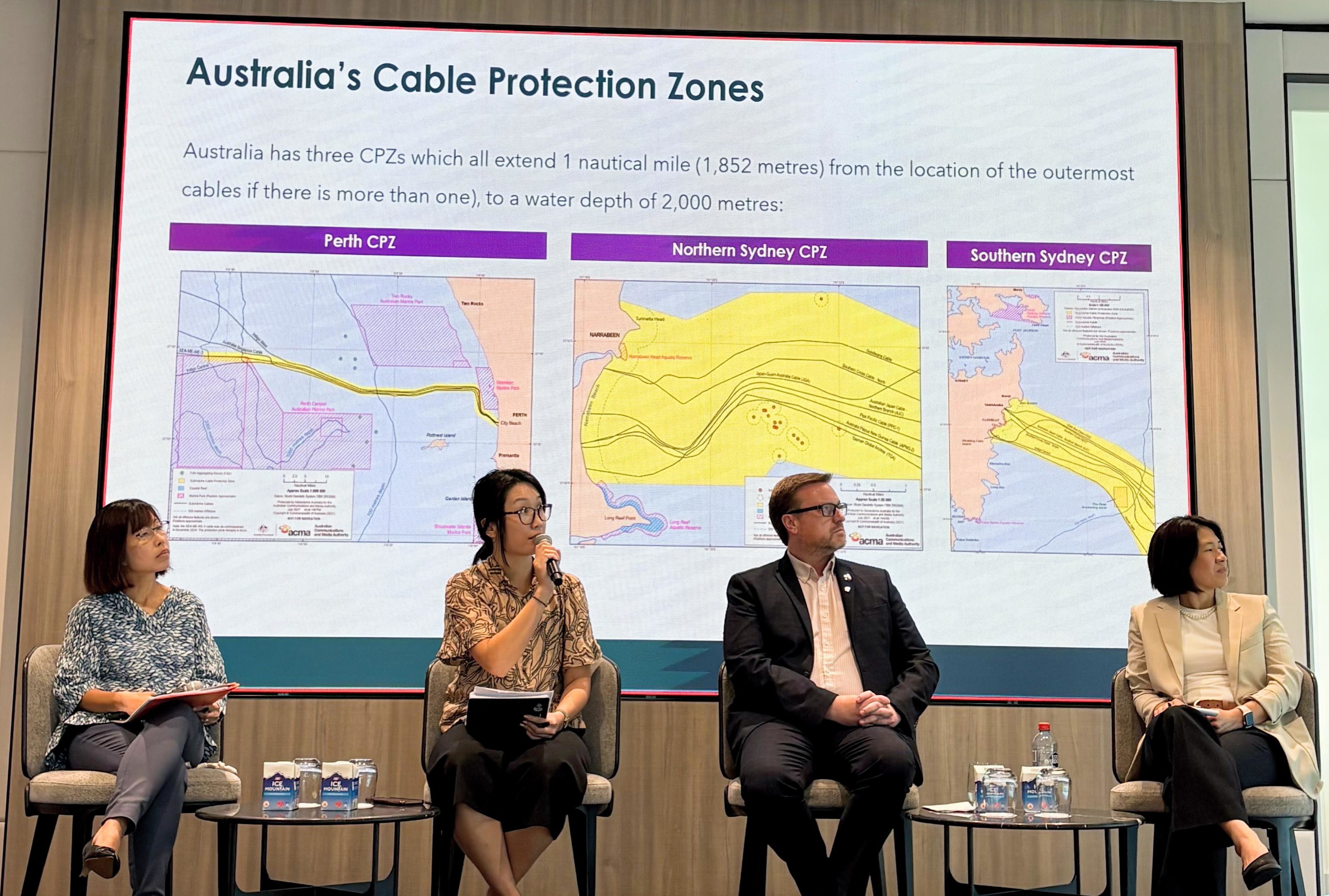 Panelists discuss cable protection zones during a CCRC workshop with ASEAN Member States. A speaker holds a microphone while presenting on stage alongside three others. 