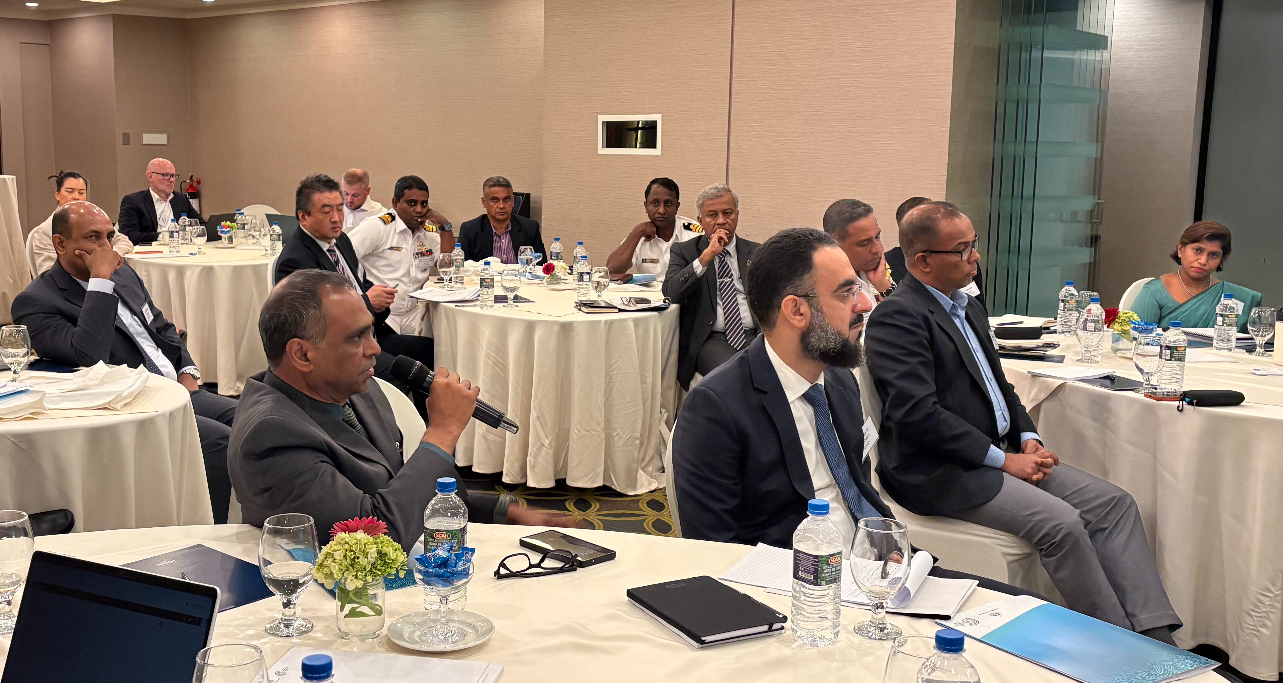 Delegates in a meeting room with white tables.