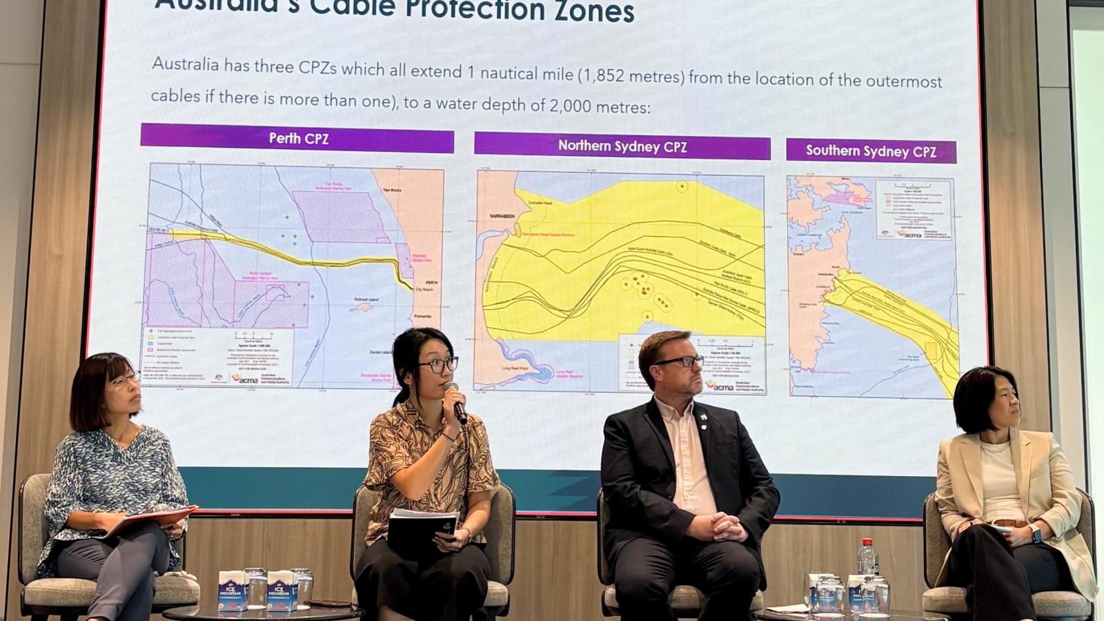 Panelists discuss cable protection zones during a CCRC workshop with ASEAN Member States. A speaker holds a microphone while presenting on stage alongside three others. 